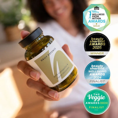 Hand holding a jar labeled 'Daily Defence' with multiple awards displayed on a blurred background
