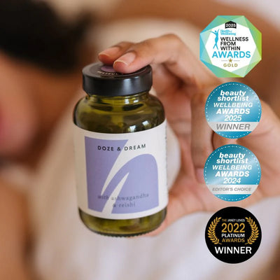 Hand holding a bottle labeled 'Doze & Dream' with wellness awards displayed.