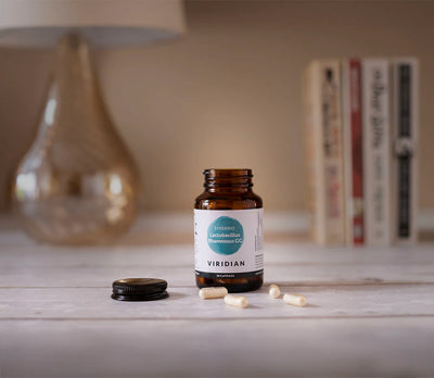 Bottle of Viridian supplements on a surface with books and a lamp in the background