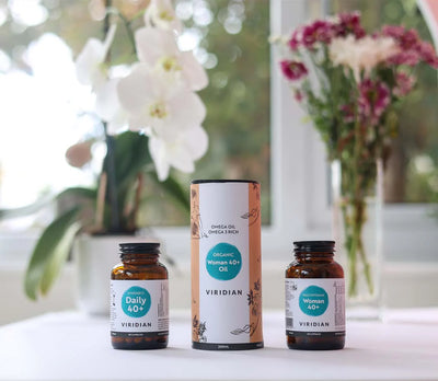 Three Viridian health products on a table with flowers in the background