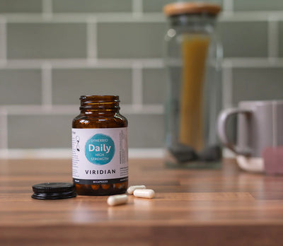 Bottle of Viridian Daily Multi Vitamin Strength on a wooden surface with a blurred kitchen background