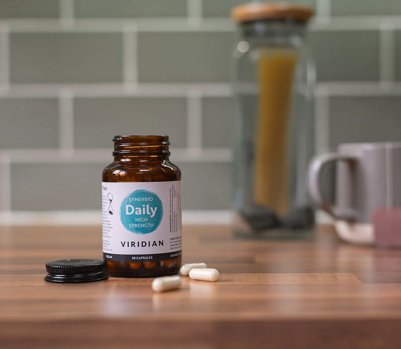 Bottle of Viridian Daily Multi Vitamin Strength on a wooden surface with a blurred kitchen background