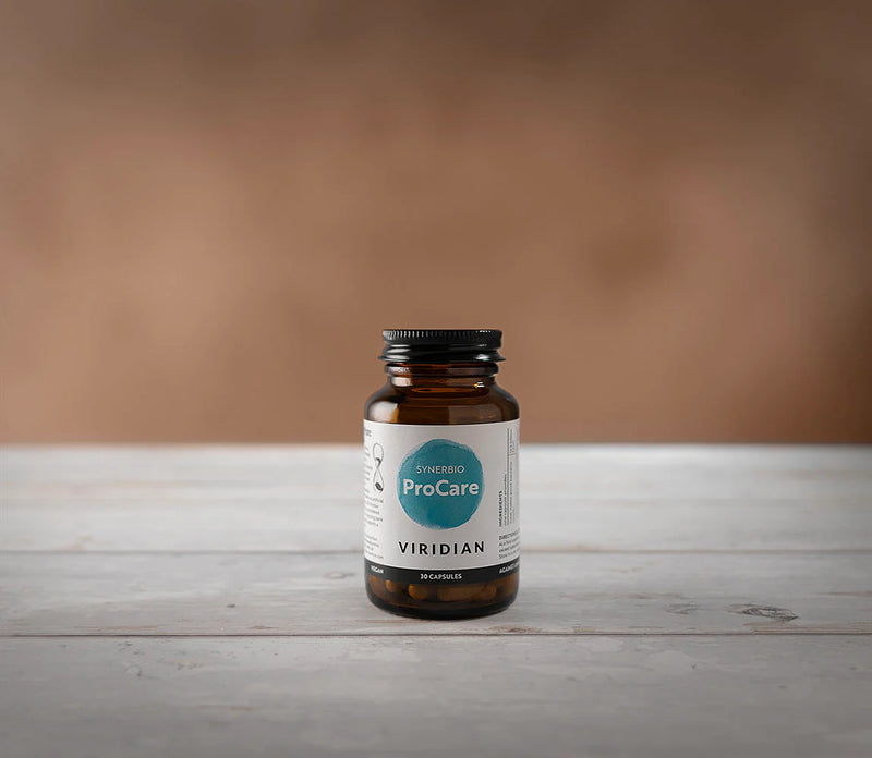 Brown supplement bottle with a label on a wooden surface and brown background