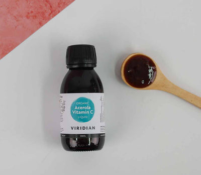Bottle of Viridian Acerola Vitamin C liquid on a white background with a wooden spoon.