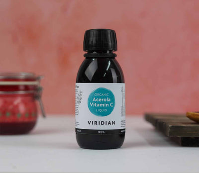 Bottle of Viridian Organic Acerola Vitamin C Liquid on a white surface with a pink background