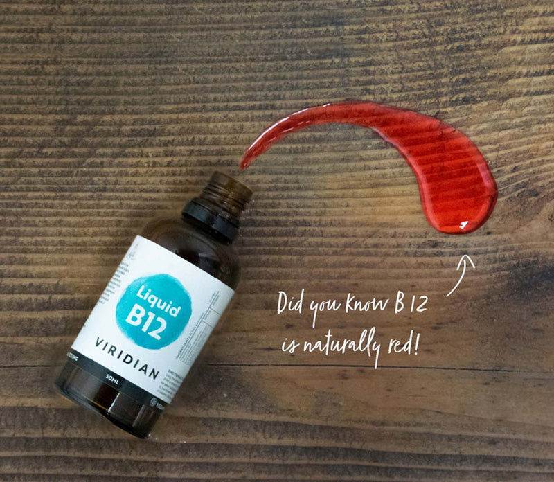 Bottle of Viridian Liquid B12 on a wooden surface with a red liquid smear and text.