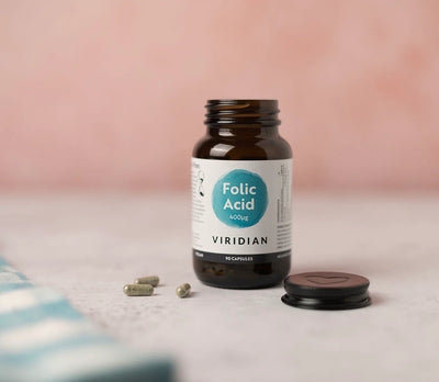 Bottle of Viridian Folic Acid on a light surface with a pink background