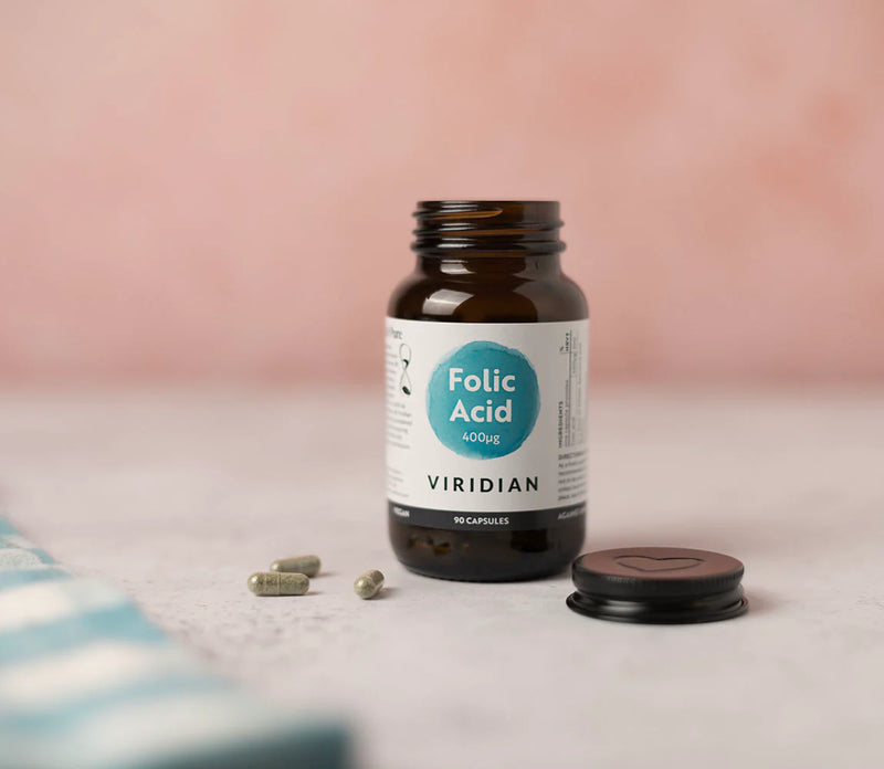 Bottle of Viridian Folic Acid on a light surface with a pink background