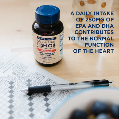 Fish oil supplement bottle on a table with crossword puzzle and pen, text about EPA and DHA benefits.