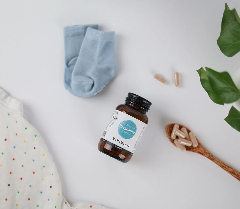 Supplement bottle with a label, blue socks, and a wooden spoon with capsules on a light background.