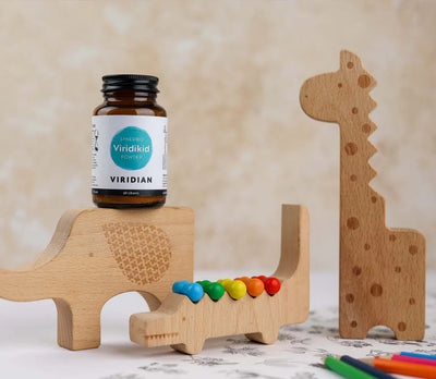 Wooden toy with colorful beads and a bottle of Viridian supplements on a neutral background