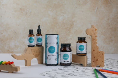 Collection of Viridian supplement bottles on a surface with wooden toys and stationery items.