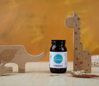 Bottle of Viridian supplements with wooden animal toys on a blurred background