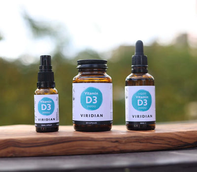 Three bottles of Viridian Vitamin D3 on a wooden surface with a blurred natural background